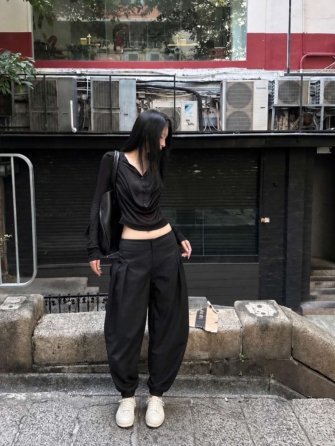 Quần baggy đen tạo khoảng rộng ở phần đùi, không ôm sát chân như quần slim fit
