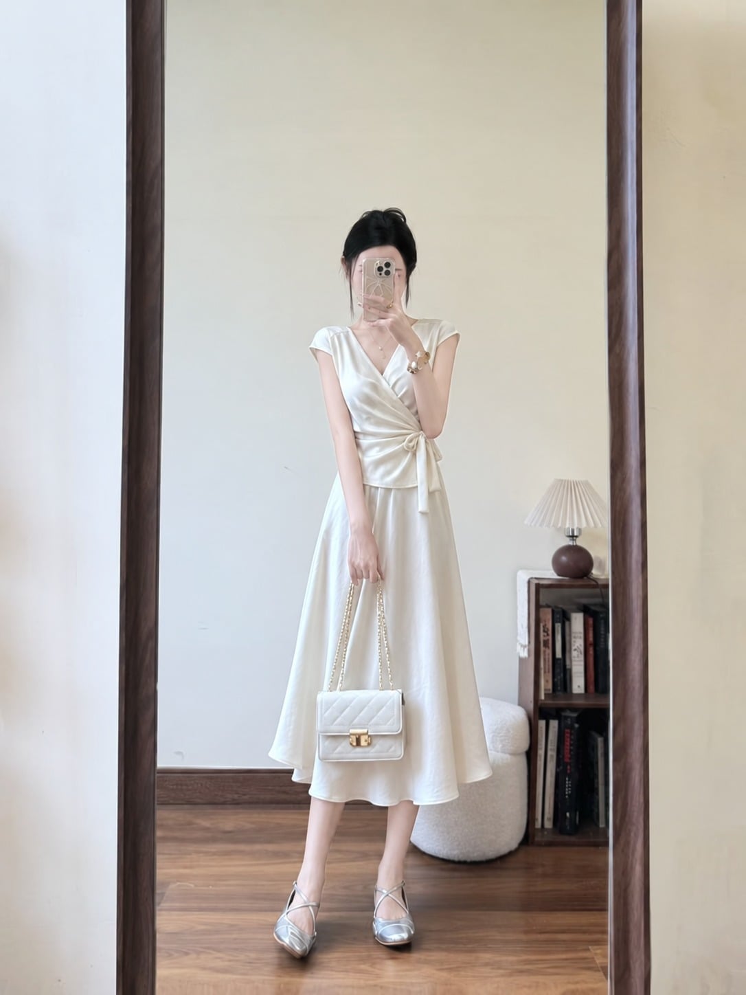 Áo quấn vạt màu kem phối chân váy midi và giày gót thấp ánh bạc
