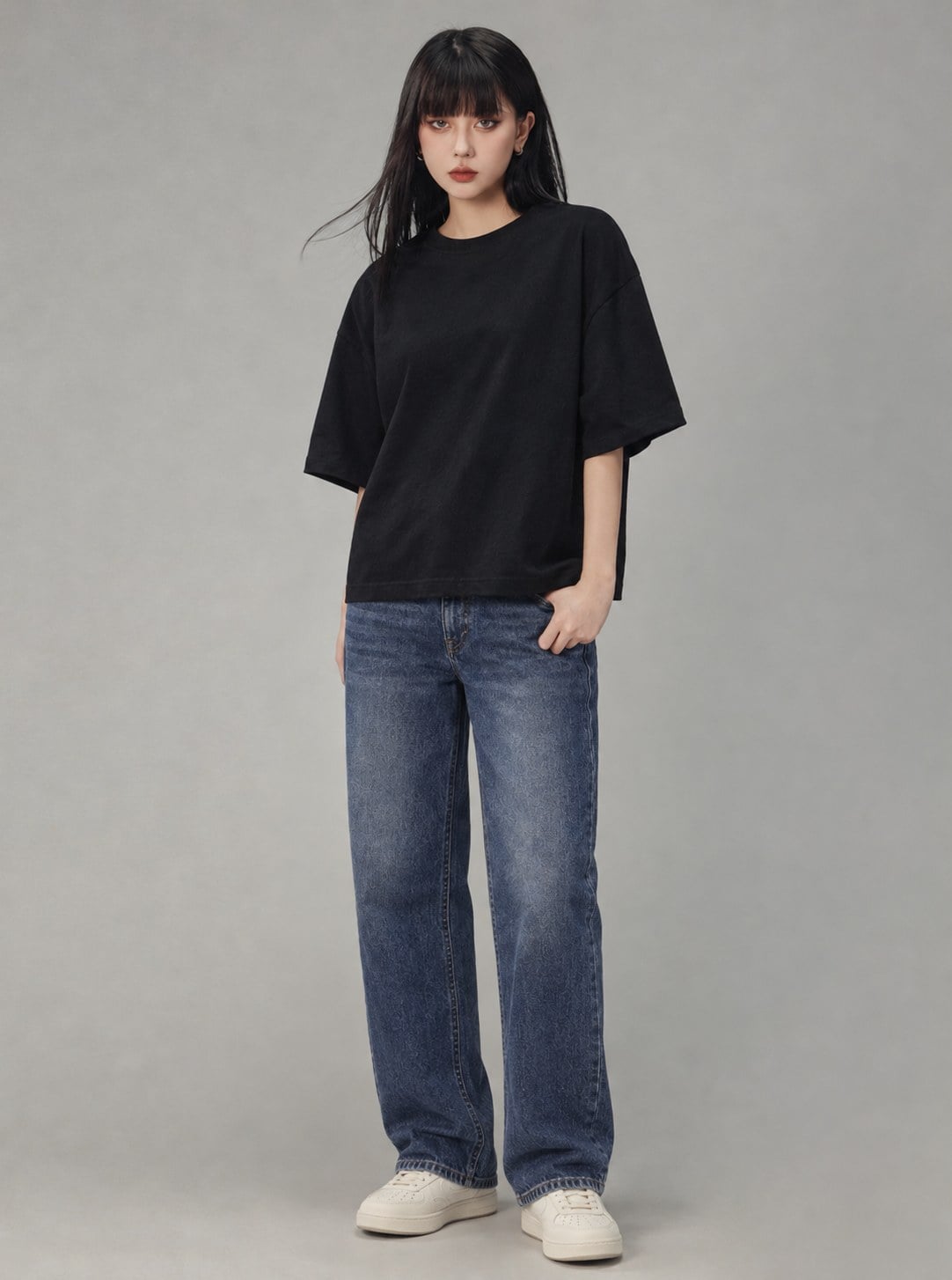 Áo thun boxy đen phối jeans ống đứng và sneaker sáng màu dáng gọn.