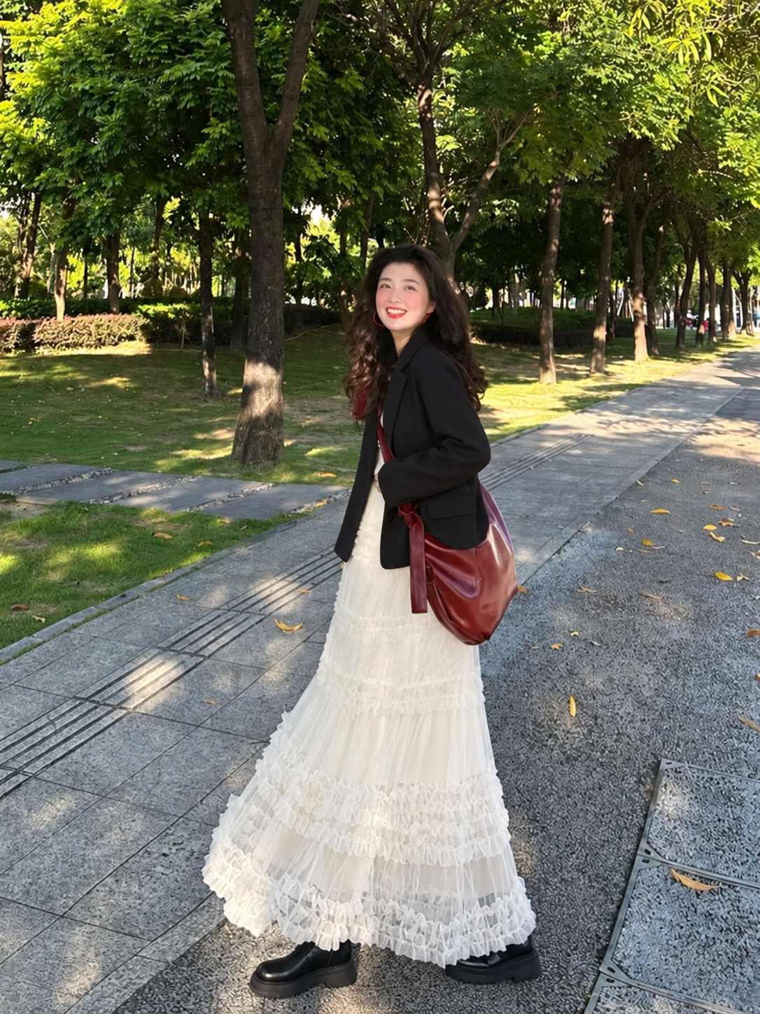 Blazer đen khoác ngoài áo trơn, phối chân váy ren dài và giày đen.