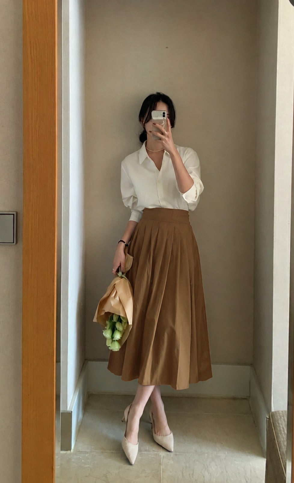 Chân váy nâu caramel phối blouse kem và giày gót thấp sáng màu giúp tổng thể nhẹ hơn