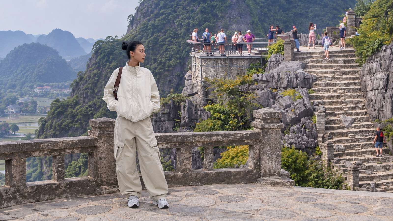 Áo khoác gió sáng màu, quần thoải mái và sneaker trên lối đá