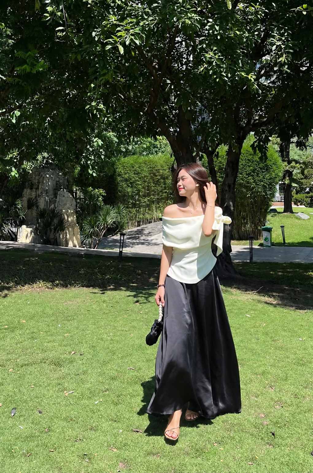 Chân váy lụa đen phối áo trắng ngà và sandal be quai mảnh
