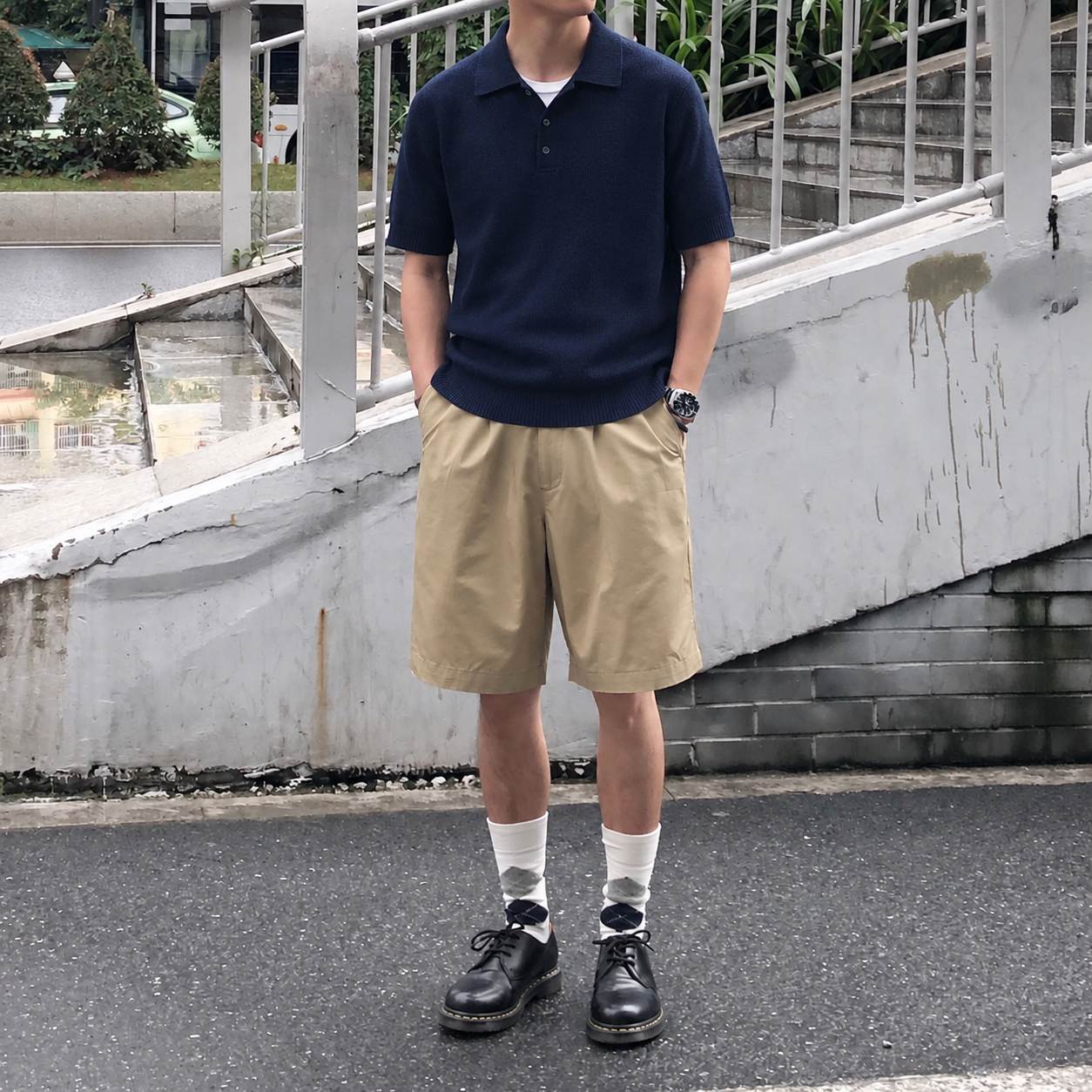 Áo polo dệt kim xanh navy phối quần sooc Bermuda màu kaki theo phong cách smart casual