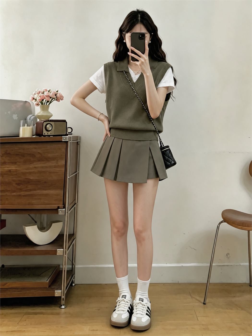 Skort xếp ly màu olive phối áo gile len và sơ mi theo phong cách preppy
