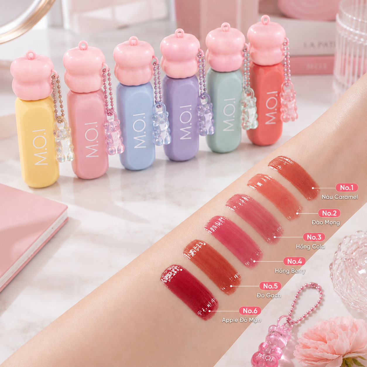 Bảng swatch 6 màu son Tint Bóng Gummy trên cánh tay: N01 Nâu Caramel, N02 Đào Mọng, N03 Hồng Cola, N04 Hồng Berry, N05 Đỏ Gạch và N06 Đỏ Mận