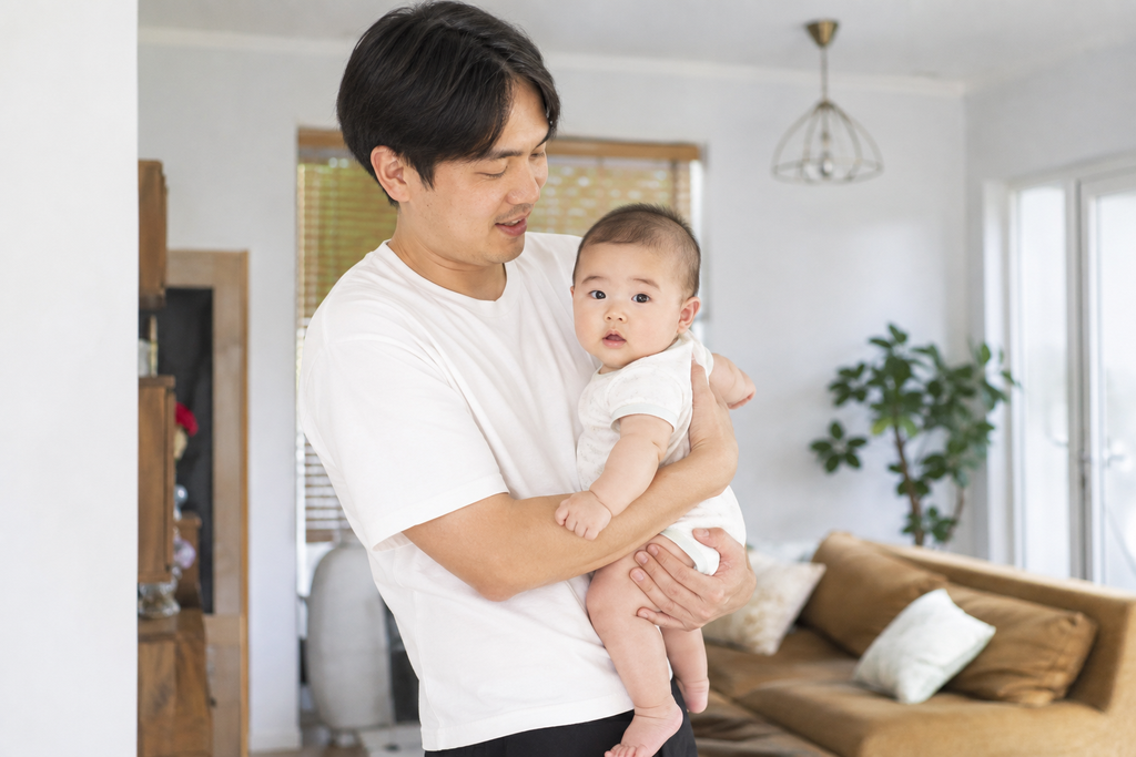 Tư thế bế vò rượu: Lưng bé áp sát ngực người bế, một tay đỡ bụng, tay kia nâng đỡ mông bé.
