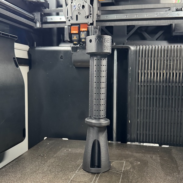 Chi tiết tay cầm công nghiệp in 3D PA12-CF có khắc mã sản phẩm trên bàn in