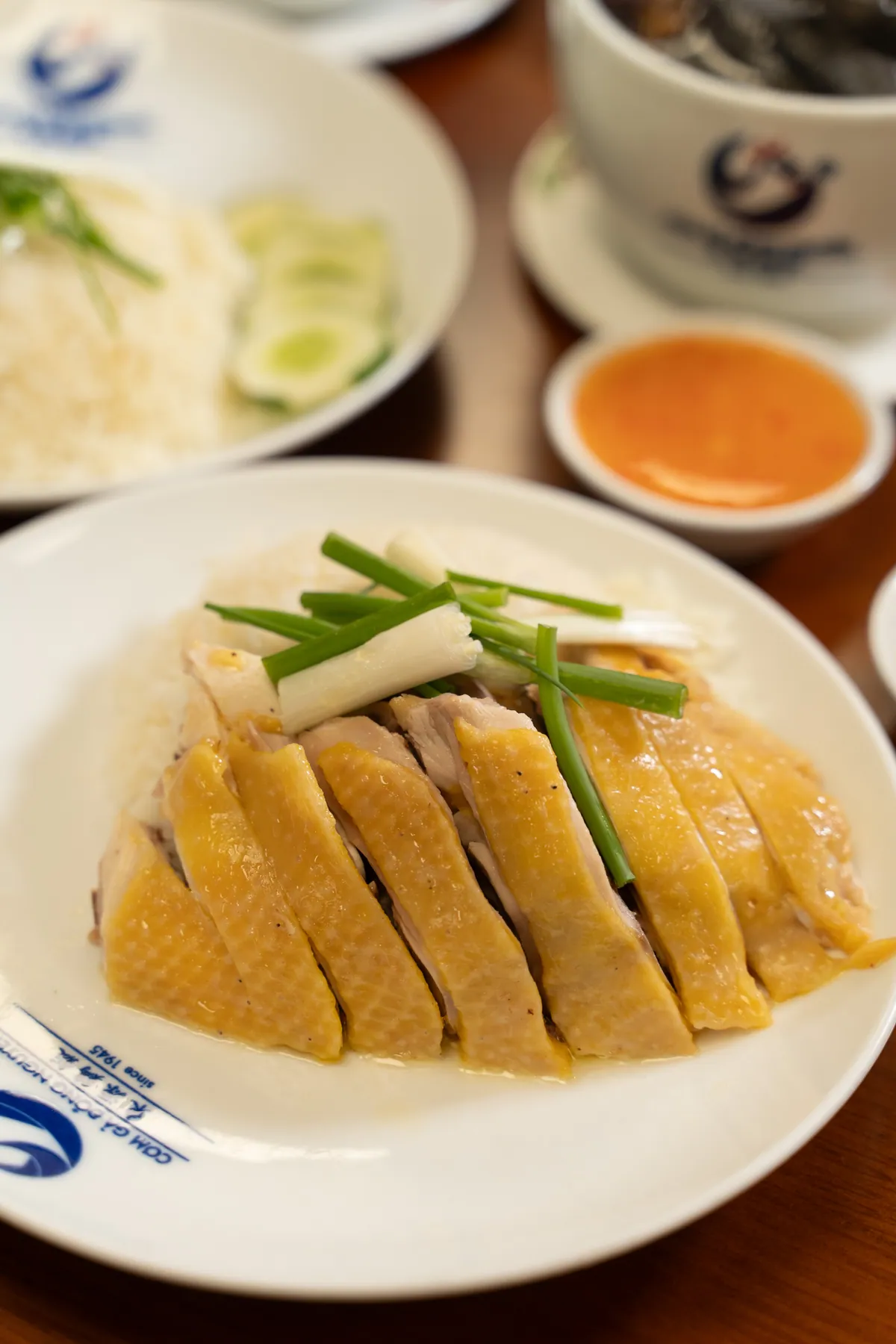 Dĩa Cơm Gà Đông Nguyên: gà mái dầu luộc chặt miếng, cơm nấu bằng nước luộc gà và chén nước chấm gừng