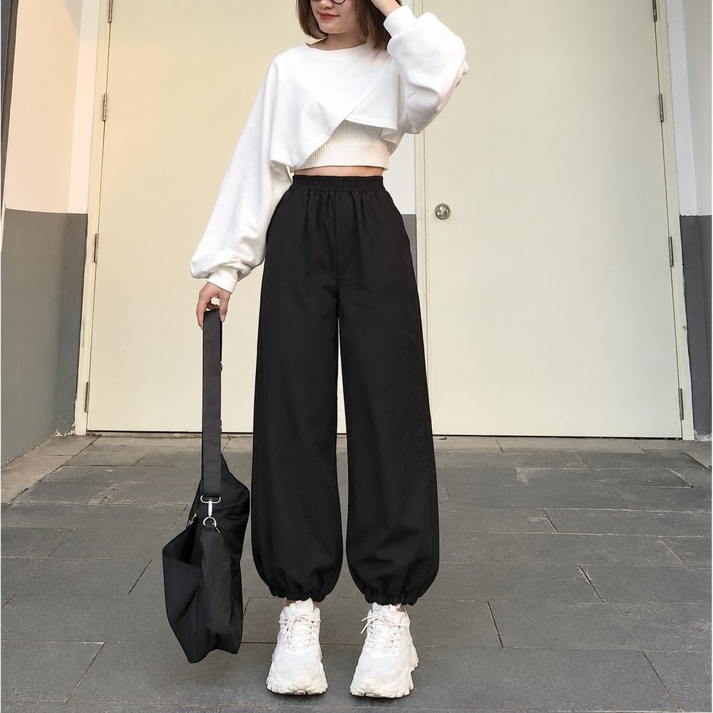 Gấu bo của quần jogger đen dừng trên sneaker trắng