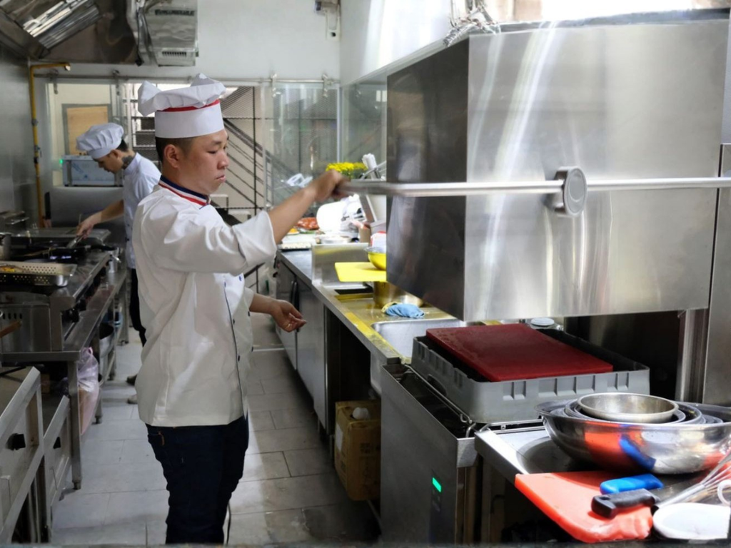 Máy rửa bát cửa sập công nghiệp đang vận hành trong bếp nhà hàng