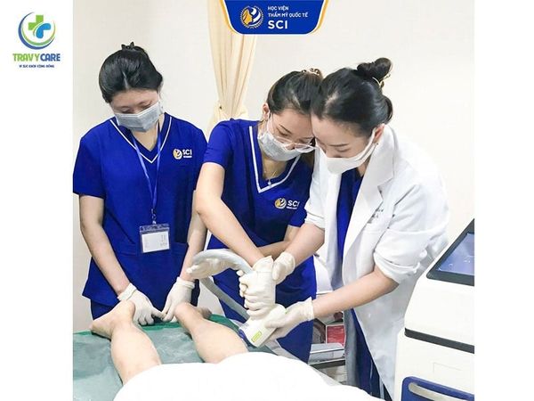 Giảng viên hướng dẫn học viên thực hành thao tác máy laser trên chân khách hàng tại địa chỉ học triệt lông chuyên nghiệp.