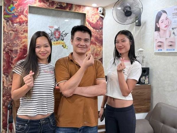Chuyên gia và khách hàng bắn tim vui vẻ sau khi trải nghiệm dịch vụ tại một địa chỉ phun môi hồng cam uy tín.