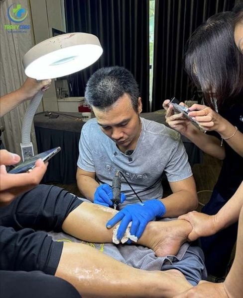 Chuyên gia Trần Mạnh Thắng đang kèm 1:1, hướng dẫn học viên cách pha mực và test màu trên vùng da nhỏ của khách hàng trước khi tiến hành che phủ vết rạn bụng.