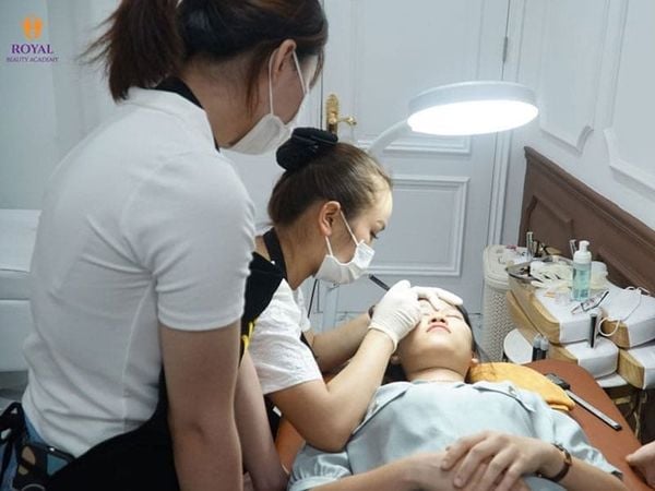 Học viên thực hành điêu khắc lông mày trên mẫu thật dưới sự hướng dẫn tại Royal Beauty Academy, một địa chỉ học điêu khắc chân mày chất lượng.