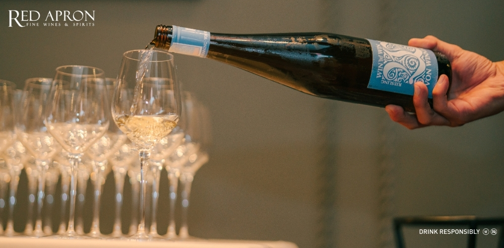 Bánh dẻo nhân trà xanh và hoa quả đặt cạnh ly vang trắng hương thảo mộc tươi, ánh sáng tự nhiên.