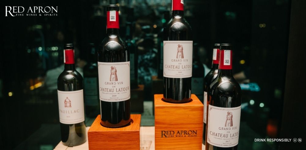 Ly rượu vang đỏ Grand Vin de Chateau Latour trên bàn degustation, thể hiện sắc đỏ ruby sâu thẳm và hương cassis, tuyết tùng, than chì đặc trưng của rượu vang Pauillac cao cấp.
