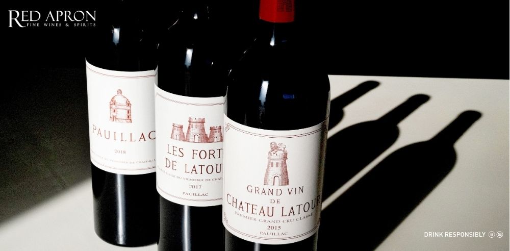 Bộ sưu tập ba dòng rượu vang Bordeaux của Chateau Latour gồm Grand Vin de Chateau Latour, Les Forts de Latour và Pauillac de Latour, xếp cạnh nhau trên phông nền hầm rượu sang trọng.