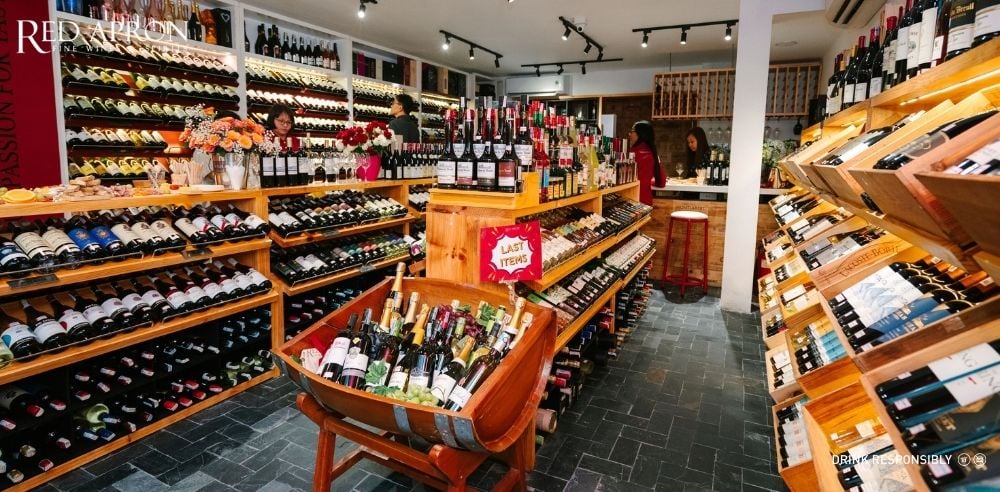 Nội thất cửa hàng rượu vang Red Apron tại Việt Nam với kệ trưng bày đầy chai, giới thiệu bộ sưu tập rượu vang Languedoc Roussillon nhập khẩu chính hãng.