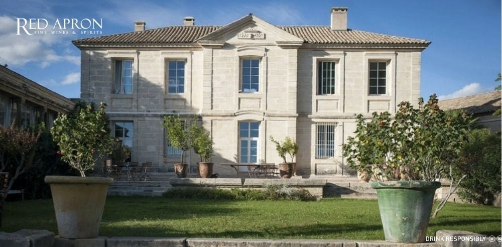 Mặt tiền château Puech Haut bằng đá sáng màu, sân hiên và vườn cây phía trước tại vùng Languedoc Roussillon, nơi sản xuất rượu vang cao cấp.