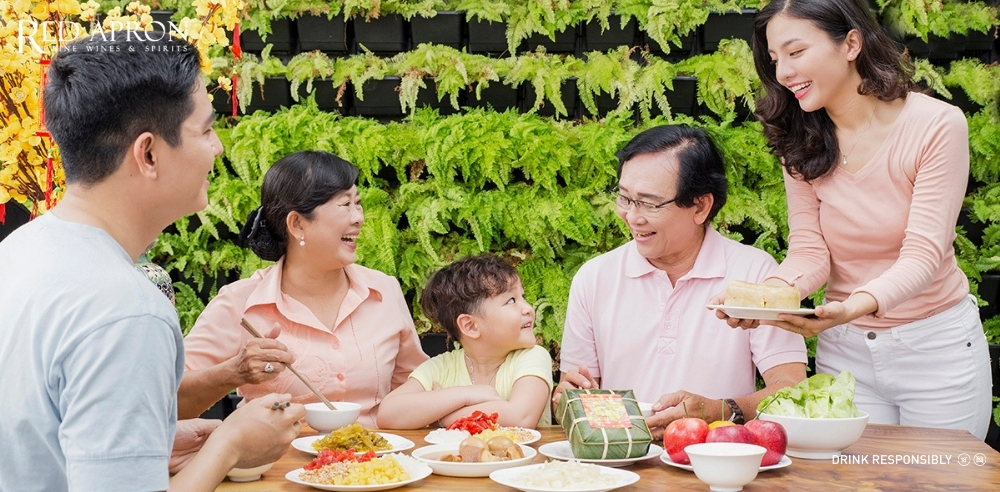 Cảnh trao tặng hộp quà Tết màu đỏ trong không gian gia đình, phù hợp ngữ cảnh chọn quà Tết cho sui gia trang trọng