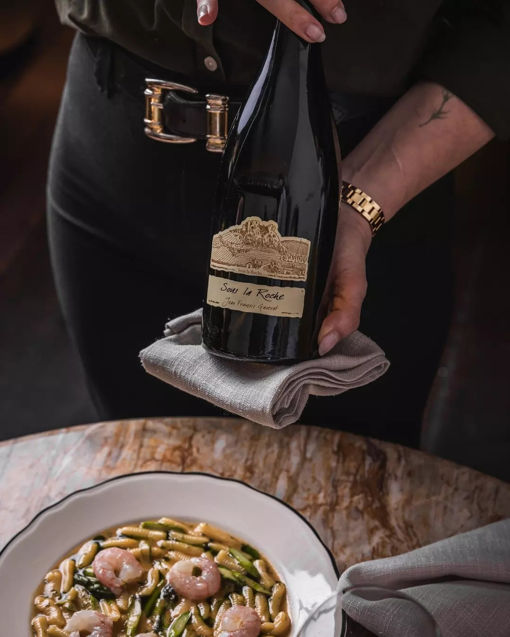 Chai Jean-François Ganevat “Sous la Roche” (Côtes du Jura) đặt cạnh món ăn, rượu vang Savagnin.