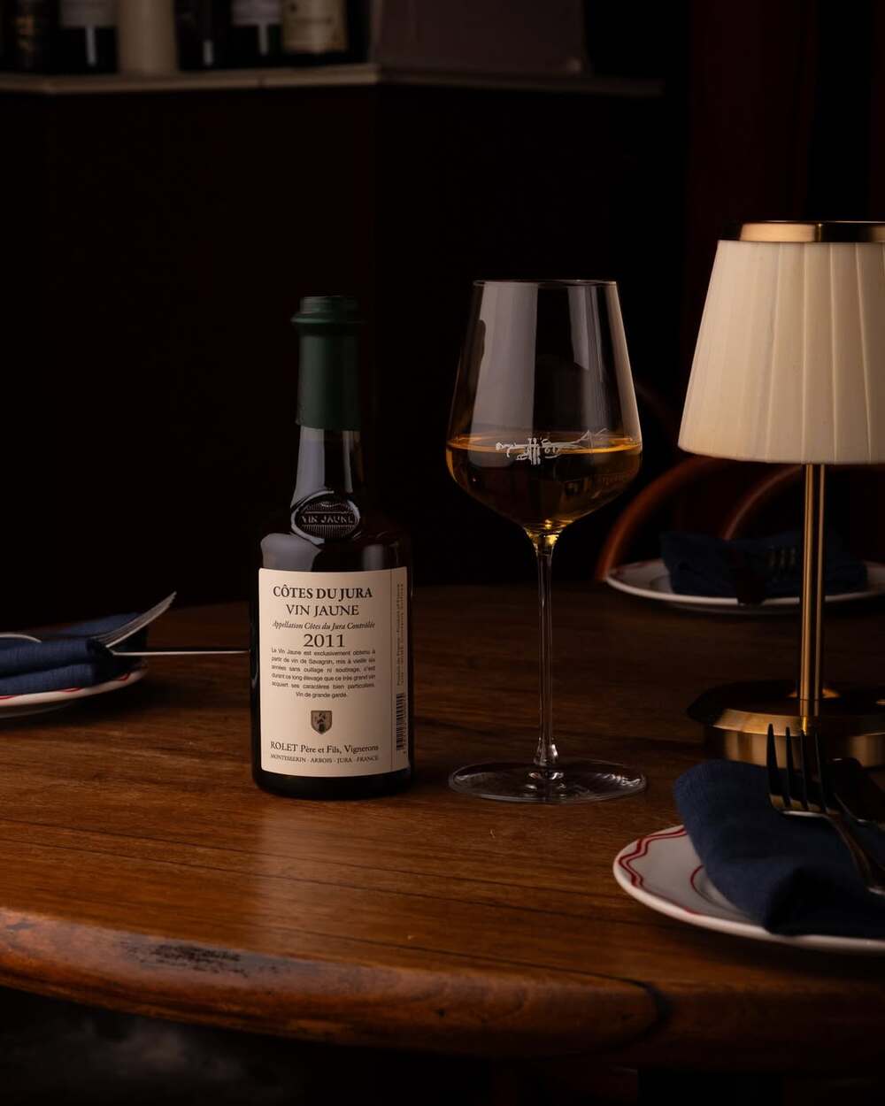 Chai Vin Jaune Côtes du Jura và ly vang trên bàn, minh họa phong cách rượu vang làm từ nho Savagnin.