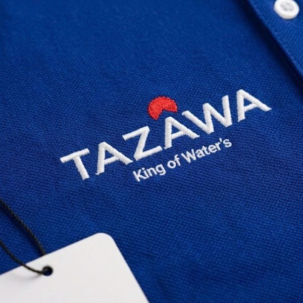 Cận cảnh logo Tazawa thêu nổi trên vải polo xanh coban, may đồng phục theo yêu cầu