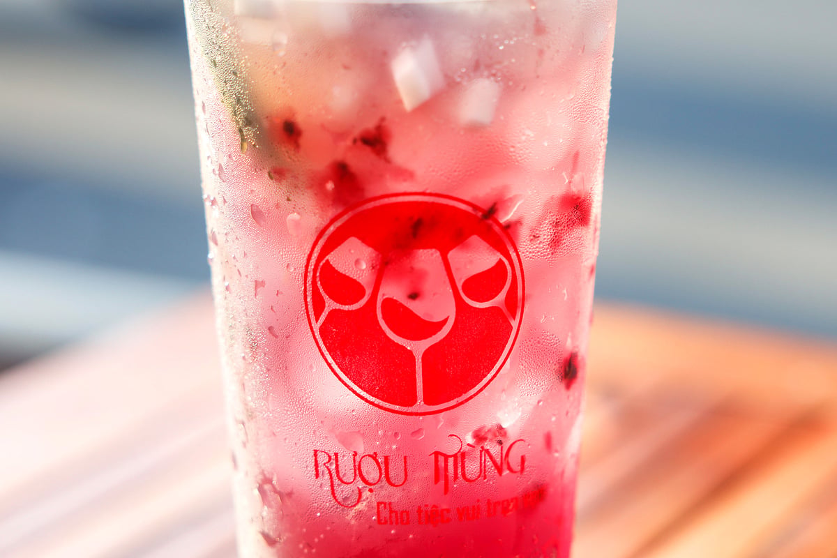 Ly mocktail hồng pha từ Rượu Mừng đặt trên bàn gỗ
