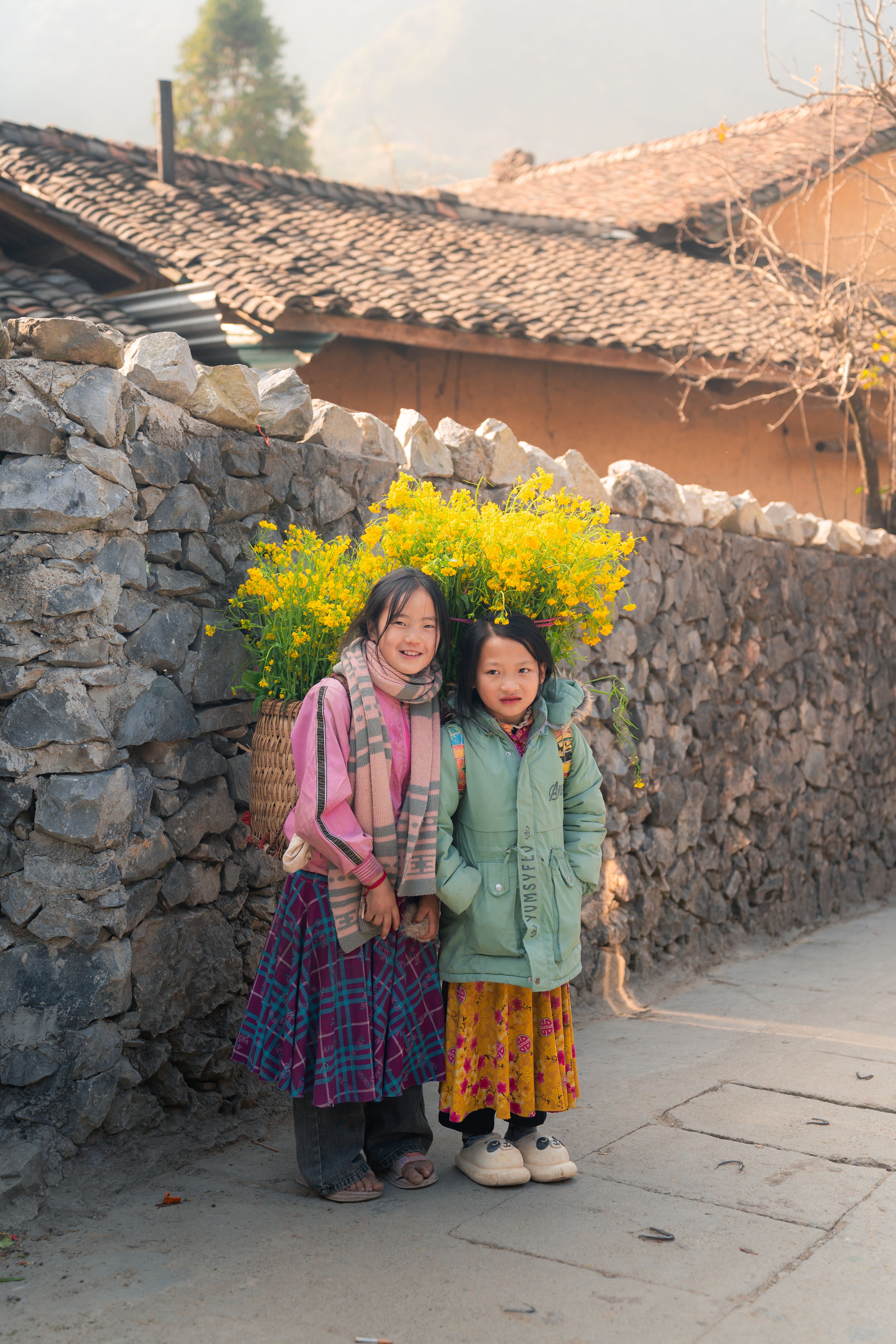 Local children carrying yellow flowers in Ha Giang spring