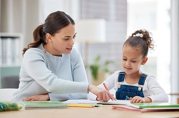 Mẹ ngồi kèm con gái làm bài tập tại bàn học