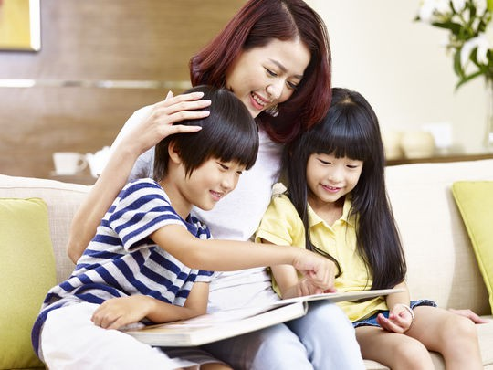 Mẹ ngồi đọc sách cùng hai con trên ghế sofa