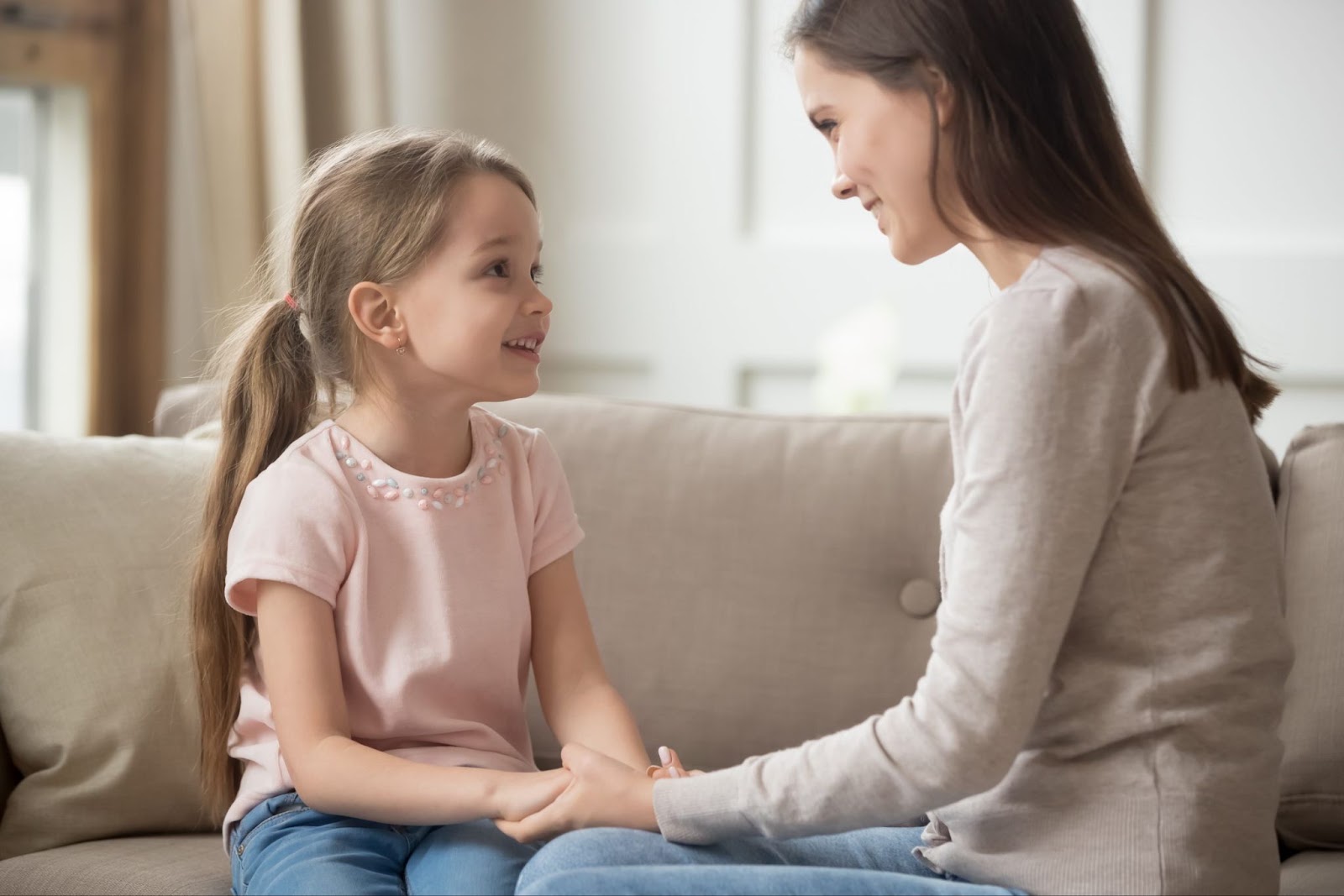 Mẹ ngồi trên ghế sofa nắm tay và trò chuyện với con gái
