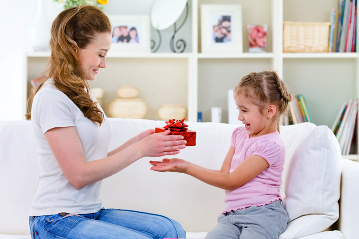 Mẹ trao hộp quà đỏ cho con gái đang ngồi trên ghế