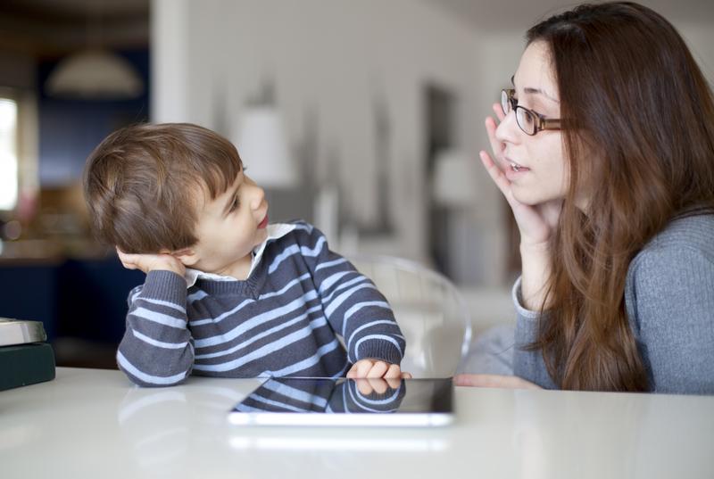 Bé trai dùng máy tính bảng, mẹ ngồi bên cạnh theo dõi