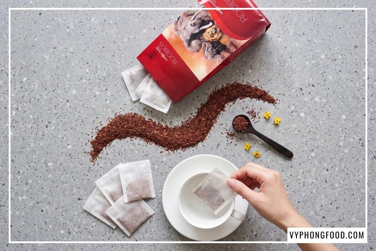 Góc chụp từ trên cao vệt lá khô cắt mịn của trà rooibos Nam Phi loại nào tốt nhất cạnh túi lọc.