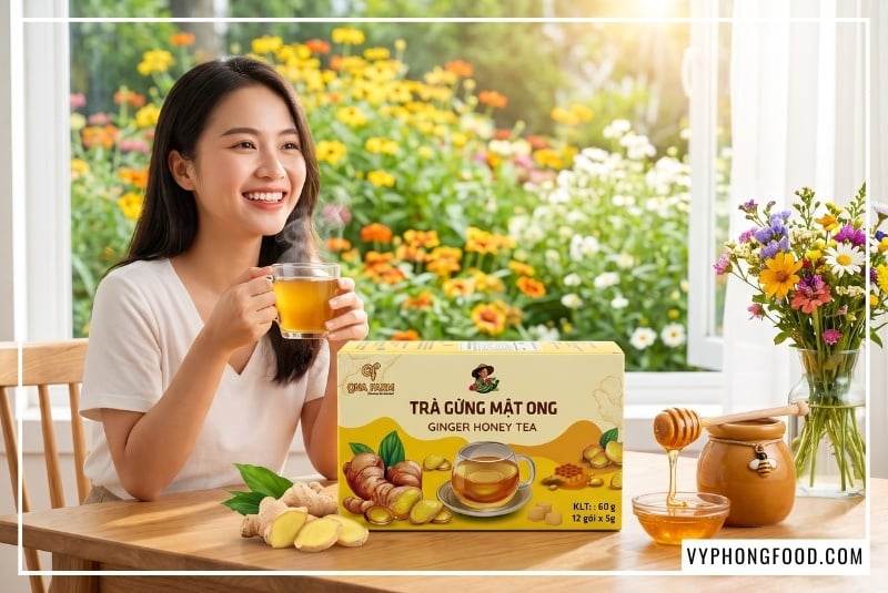 Hộp trà gừng mật ong hòa tan QNA Farm 60g đặt trên bàn gỗ cạnh ly trà ấm bốc khói nhẹ và hũ mật ong trong buổi sáng đầy nắng, minh họa trực quan cho bài viết hướng dẫn làm trà gừng mật ong tốt cho sức khỏe tại vyphongfood.com.
