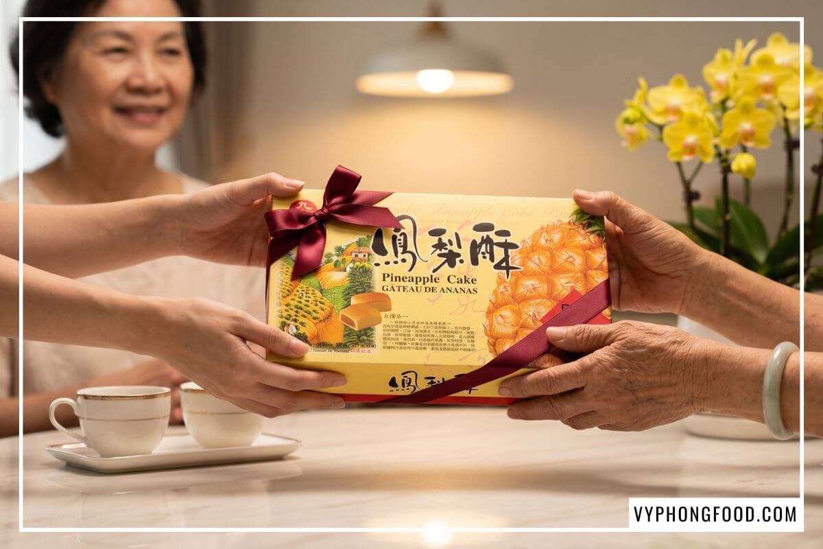 Đôi tay trao tặng hộp bánh dứa nổi tiếng Đài Loan Nice Choice thắt ruy băng đỏ bên người mẹ.
