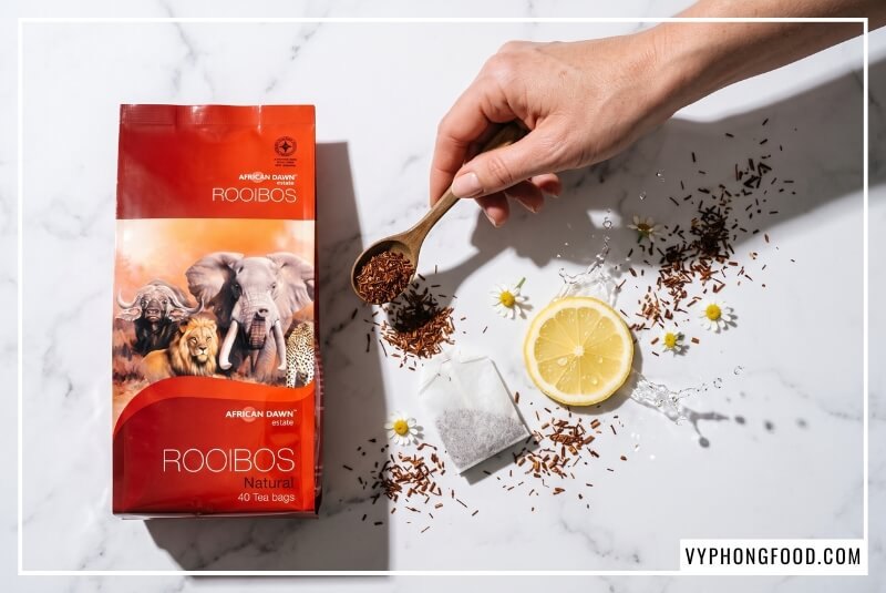 Lá trà kim khô và muỗng gỗ cạnh gói trà rooibos có tốt cho sức khỏe không trên đá cẩm thạch