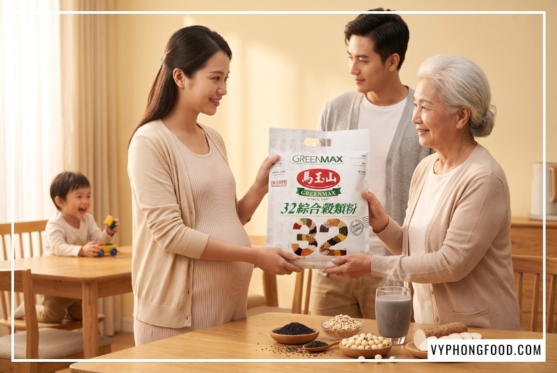 Gia đình ba thế hệ ấm cúng bên bàn ăn mẹ bầu bí đoan trang trân trọng biếu bà túi ngũ cốc cho bà bầu 3 tháng đầu mè đen Greenmax bên cạnh ly ngũ cốc ấm nóng sánh mịn.