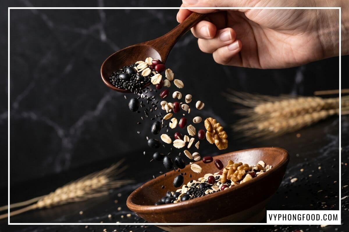 Thìa gỗ rót hạt đậu đen và mè đen giàu đạm cho chế độ ăn thuần chay trên bàn đá cẩm thạch.