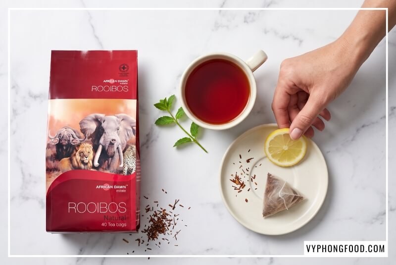 Người phụ nữ thả chanh vào tách trà thể hiện công dụng của trà thảo mộc rooibos Nam Phi cho tiêu hóa.