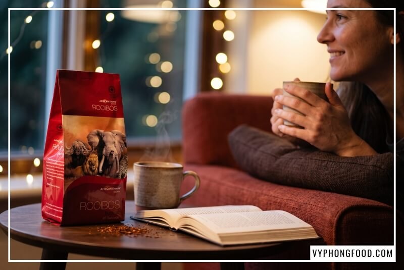 Nhân vật mỉm cười ôm ly trà ấm làm nổi bật công dụng của trà thảo mộc rooibos Nam Phi giúp ngủ ngon.