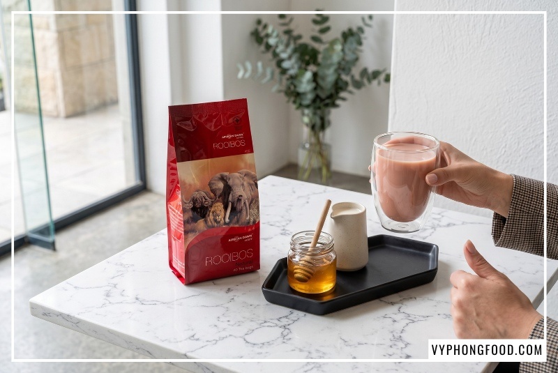 Bao bì Hồng trà Rooibos African Dawn đặt cạnh tách trà sữa gốm Bát Tràng xanh coban và mẹt tre nguyên liệu đường phèn gừng tươi sữa dừa tại Trung Nguyên Legend, giải pháp nguyên liệu làm trà sữa không caffeine từ vyphongfood.com.
