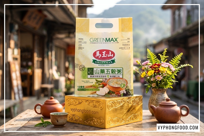 Túi cháo ngũ cốc dinh dưỡng từ khoai mỡ và các loại hạt Greenmax Đài Loan đặt trên bục vàng mây cuộn khắc vyphongfood.com, bối cảnh bàn đá mộc mạc phố cổ Thập Phần ngập nắng sớm hắt sáng HDR nét căng. Sản phẩm nhập khẩu ngũ cốc Đài Loan uy tín.