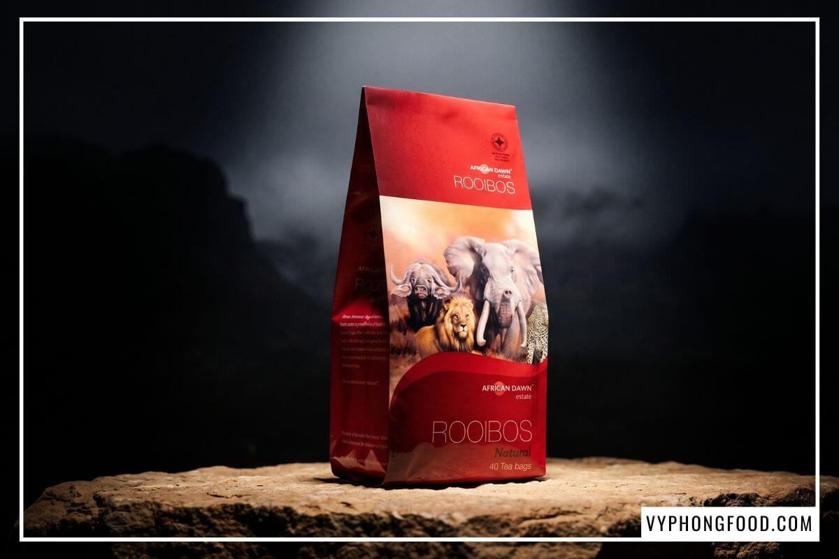 Hộp trà African Dawn in biểu tượng chứng nhận PDO đặt trên tảng đá sa thạch ở góc tối.