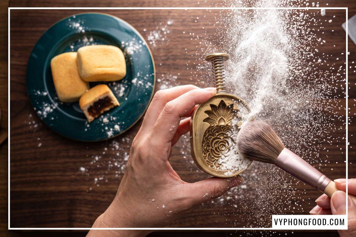 Cọ lông mềm đang quét lớp tinh bột bắp mỏng bay lơ lửng vào rãnh chiếc khuôn lò xo mini.
