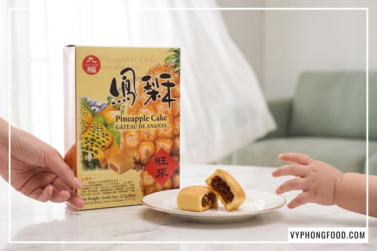 Hộp bánh dứa Đài Loan Nice Choice 227g đứng cạnh đĩa gốm đựng chiếc bánh bẻ đôi bóng bẩy phần nhân dứa bí đao.