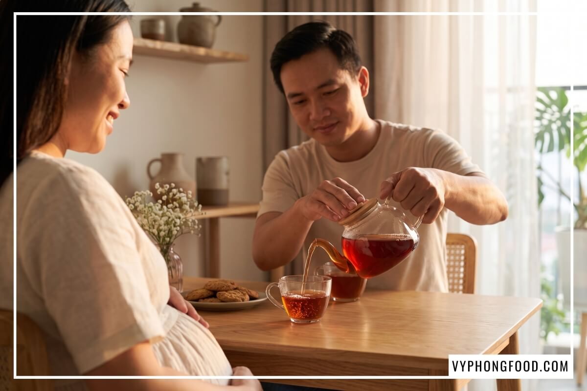 Người chồng rót trà thảo mộc rooibos Nam Phi cho mẹ bầu từ ấm thủy tinh trong ánh hoàng hôn ấm áp.