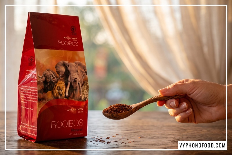 Chuyên gia chuẩn bị muỗng lá trà rooibos sấy khô bên bao bì African Dawn giúp bảo toàn công dụng của trà thảo mộc.